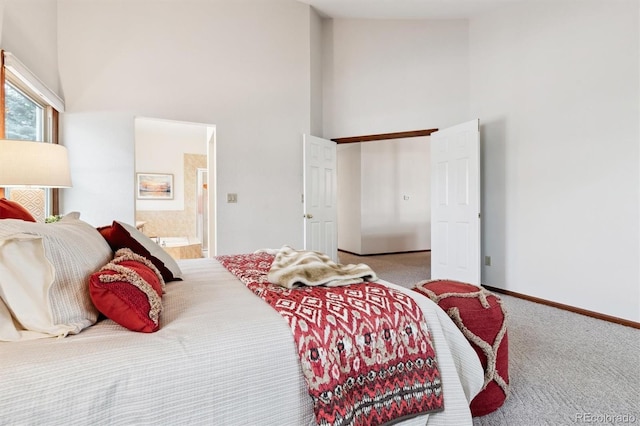 carpeted bedroom featuring connected bathroom and a high ceiling