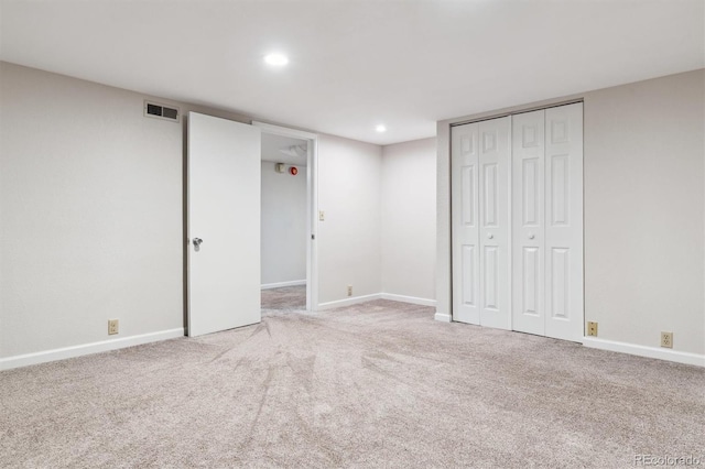 unfurnished bedroom featuring light carpet and a closet