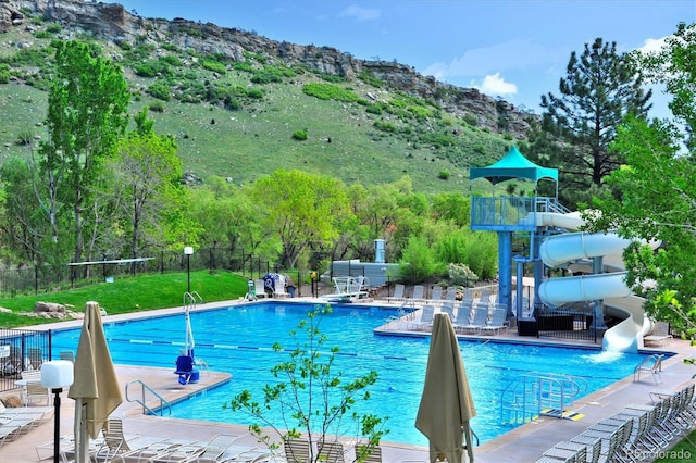 view of pool with a patio area, a mountain view, and a water slide