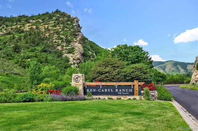 community sign with a mountain view and a lawn