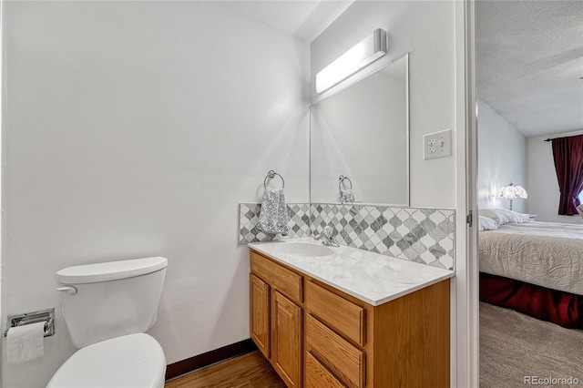 bathroom featuring tasteful backsplash, vanity, a textured ceiling, and toilet