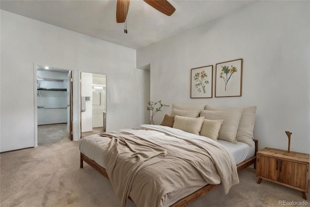 bedroom with light carpet, ceiling fan, a walk in closet, and ensuite bathroom