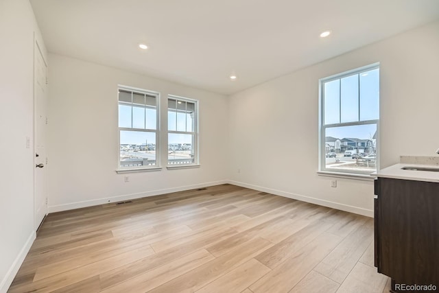 unfurnished room with sink and light hardwood / wood-style floors