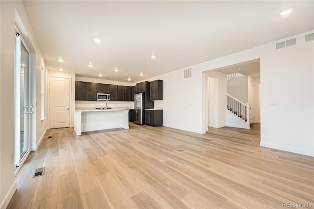 unfurnished living room featuring sink and light hardwood / wood-style floors