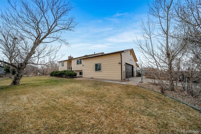 back of property with a garage, a chimney, and a lawn