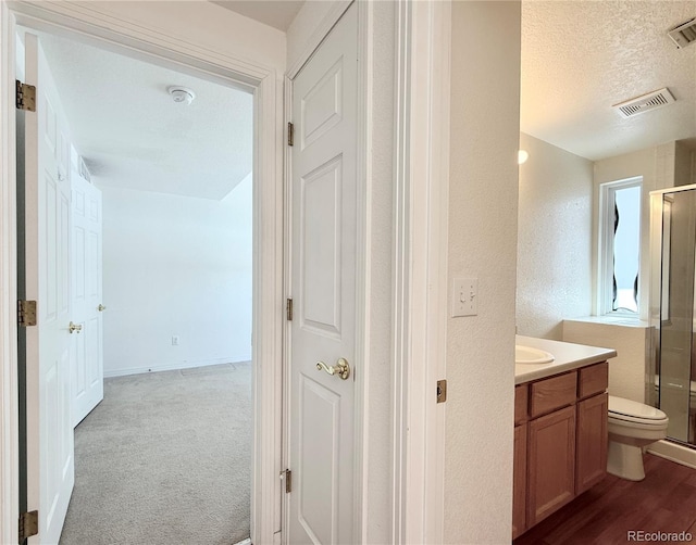 bathroom with hardwood / wood-style floors, vanity, a textured ceiling, toilet, and walk in shower