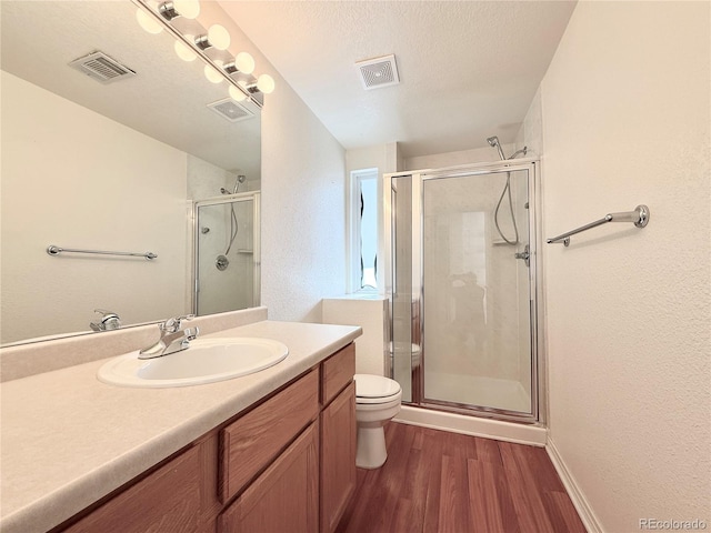 bathroom featuring toilet, an enclosed shower, a textured ceiling, vanity, and hardwood / wood-style flooring