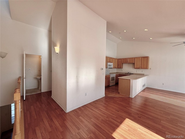 kitchen with dark wood-type flooring, sink, high vaulted ceiling, kitchen peninsula, and white appliances