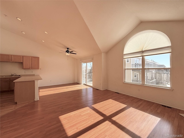 unfurnished living room with sink, vaulted ceiling, hardwood / wood-style floors, and ceiling fan