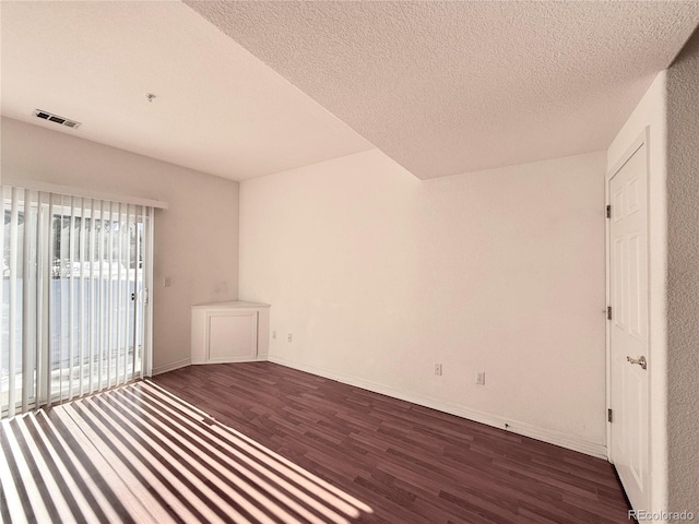 spare room featuring dark hardwood / wood-style floors and a textured ceiling