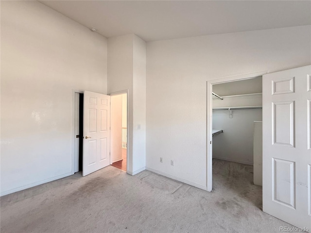 unfurnished bedroom with a walk in closet, a closet, and light carpet