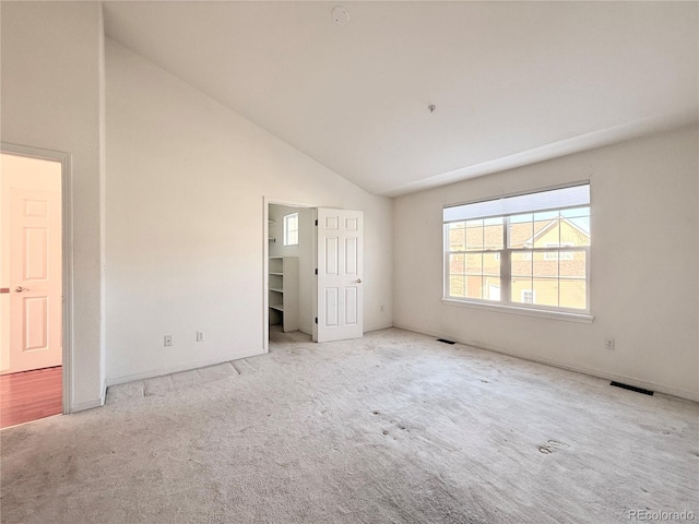 unfurnished bedroom featuring light colored carpet and high vaulted ceiling