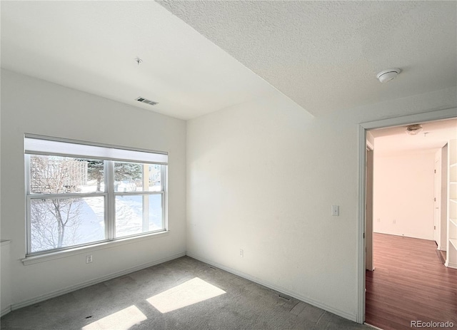 empty room featuring dark carpet and a textured ceiling