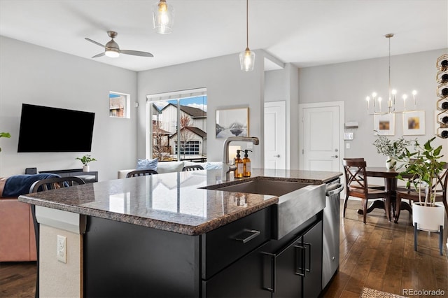 kitchen with open floor plan, dark cabinetry, dark wood finished floors, a center island with sink, and a sink