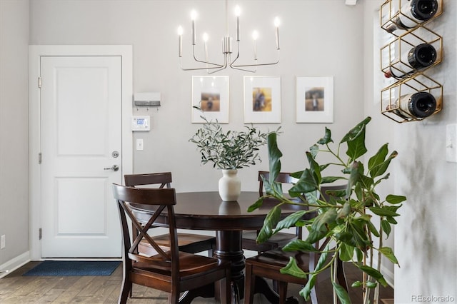dining space with baseboards, wood finished floors, and a chandelier