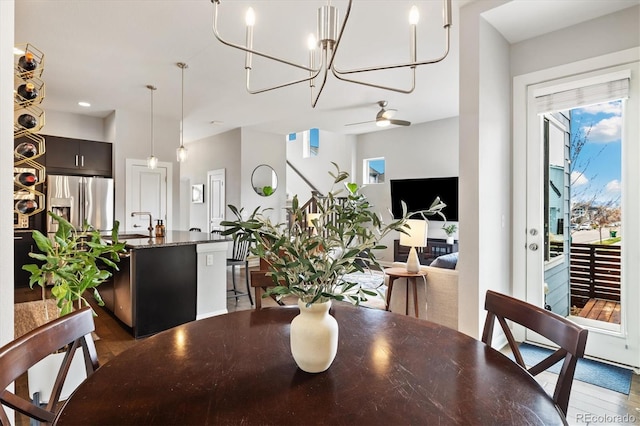 dining area featuring ceiling fan with notable chandelier and dark wood finished floors