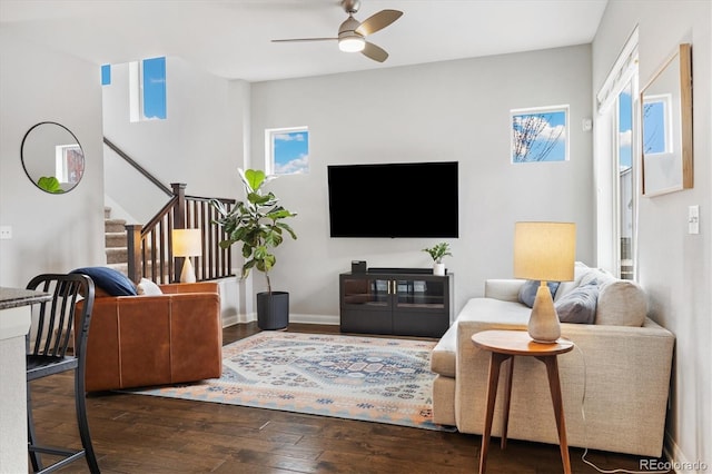living area with baseboards, stairway, a ceiling fan, and wood-type flooring