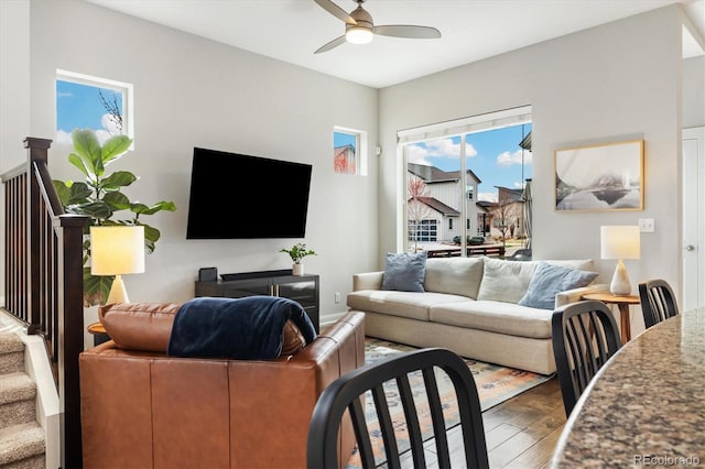 living area with wood finished floors, stairway, and a ceiling fan