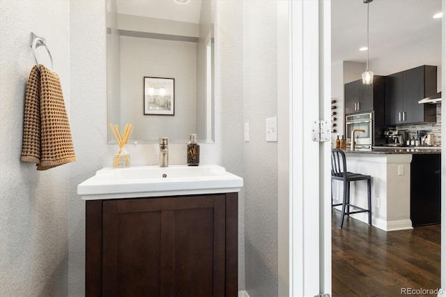 bathroom with backsplash, vanity, and wood finished floors