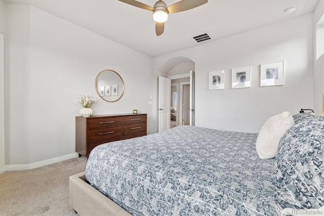 carpeted bedroom featuring arched walkways, baseboards, ceiling fan, and visible vents