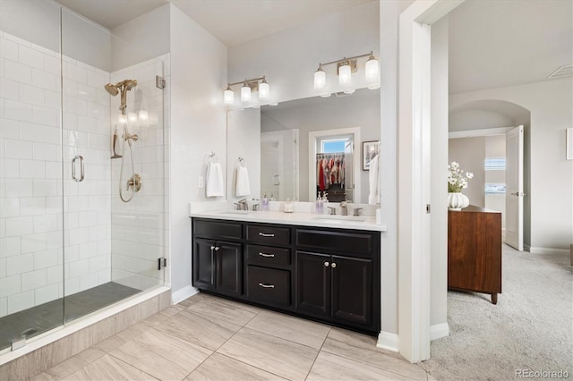 bathroom with baseboards, double vanity, a sink, and a stall shower