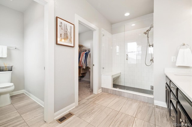 bathroom featuring toilet, a shower stall, a walk in closet, and visible vents