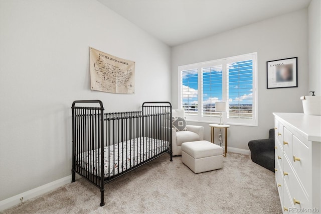 bedroom with light carpet, baseboards, and a nursery area
