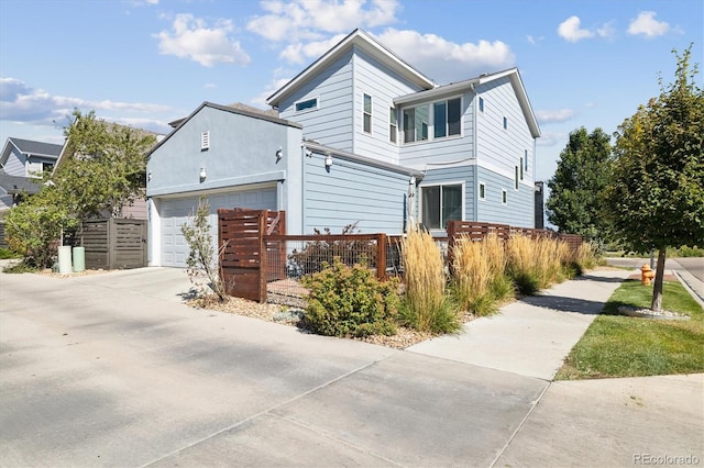 view of front facade featuring driveway, an attached garage, and a fenced front yard
