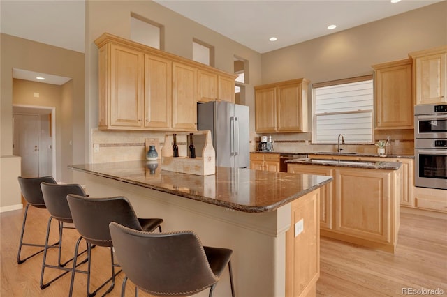 1001 Deer Clover Way, Castle Pines, CO 80108 - kitchen featuring appliances with stainless steel finishes, light brown cabinetry, light wood-style flooring, a breakfast bar area, and recessed lighting