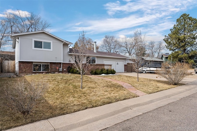 tri-level home featuring concrete driveway, an attached garage, fence, a front lawn, and brick siding