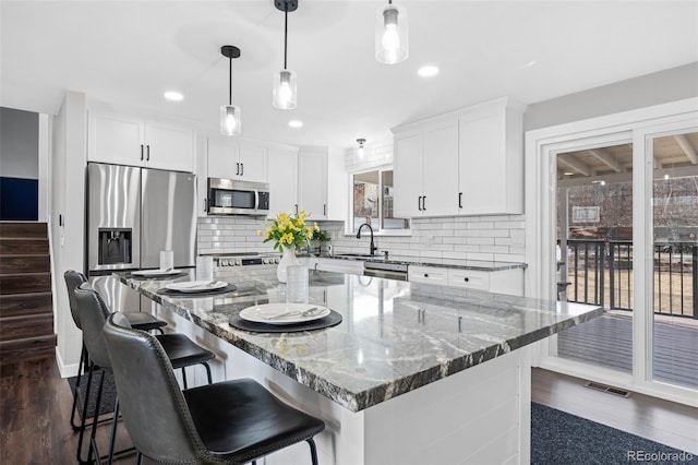 kitchen with stainless steel appliances, dark wood-style flooring, white cabinetry, and tasteful backsplash