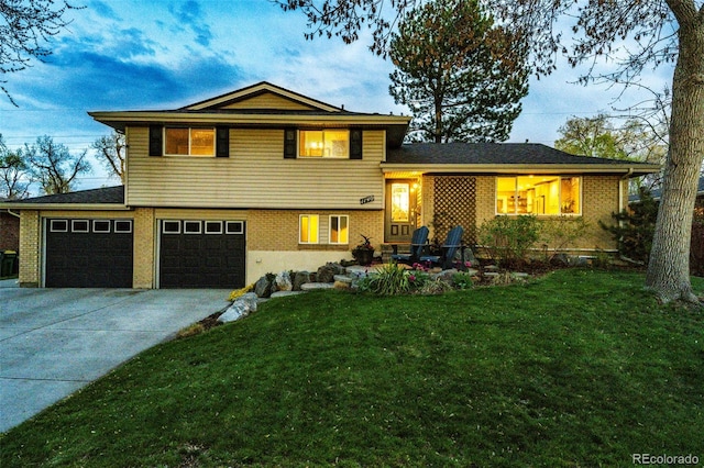 split level home with concrete driveway, brick siding, an attached garage, and a front lawn
