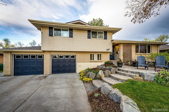 split level home with a garage, concrete driveway, and brick siding