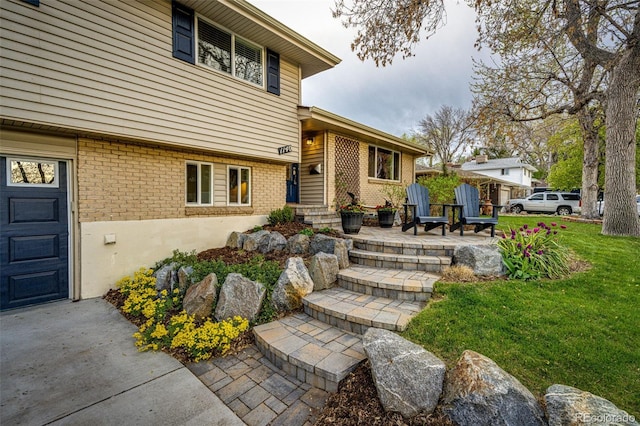 view of exterior entry with a yard and brick siding