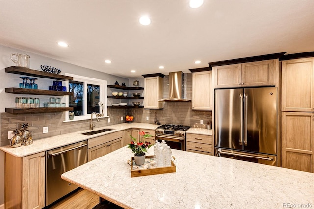 kitchen featuring open shelves, light stone countertops, wall chimney exhaust hood, a sink, and stainless steel appliances