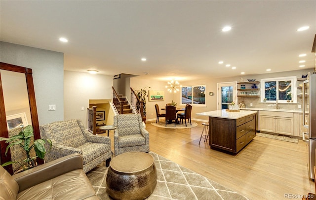 living room featuring recessed lighting, an inviting chandelier, light wood finished floors, and stairway