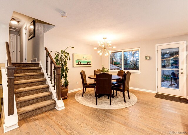 dining room featuring baseboards, a chandelier, stairway, and light wood-style floors