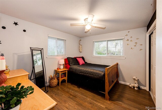 bedroom featuring baseboards, ceiling fan, wood finished floors, and multiple windows