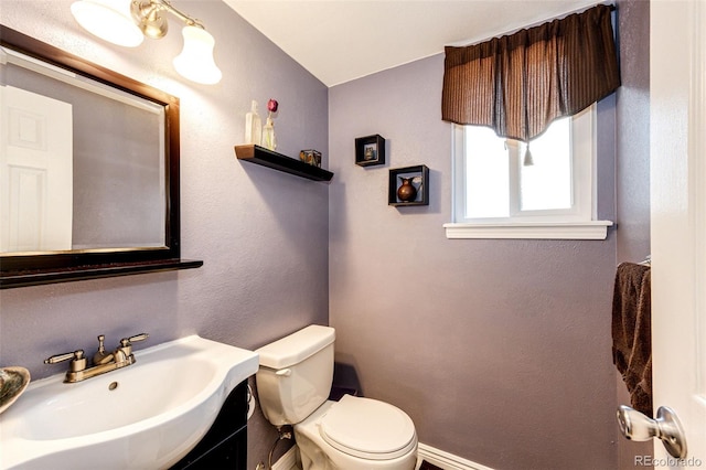 bathroom featuring a sink, baseboards, and toilet