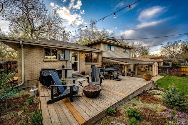 rear view of house with a wooden deck, brick siding, a fenced backyard, an outdoor fire pit, and outdoor dining space