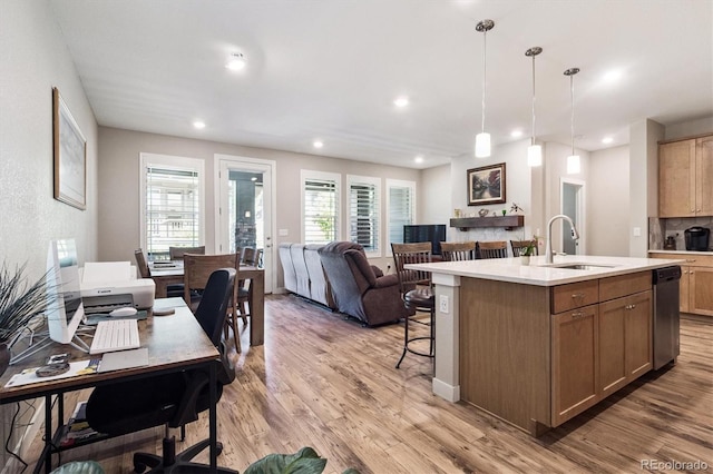 1976 Canyonpoint Ln, Castle Pines, CO 80108 - kitchen with stainless steel dishwasher, light wood-style floors, light countertops, a breakfast bar area, and a center island with sink