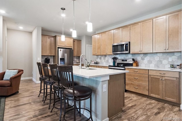 1976 Canyonpoint Ln, Castle Pines, CO 80108 - kitchen with stainless steel appliances, light wood-style flooring, a breakfast bar, tasteful backsplash, and recessed lighting