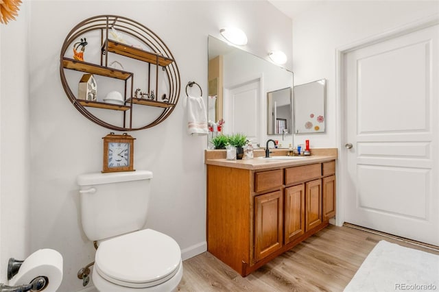 bathroom featuring wood-type flooring, toilet, and vanity