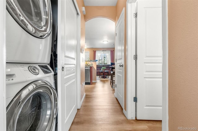 laundry area with stacked washer / dryer and light wood-type flooring