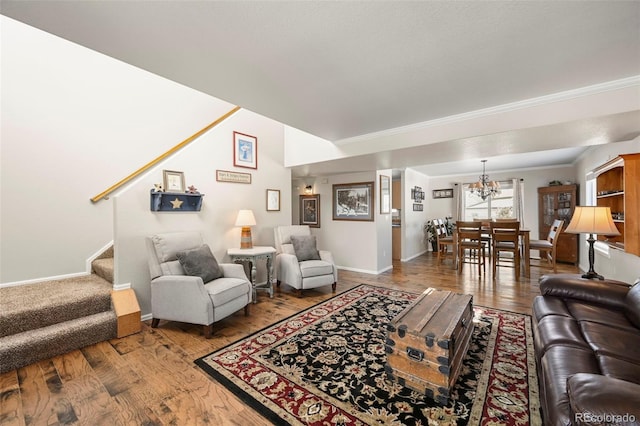 living area with baseboards, wood finished floors, stairs, crown molding, and a chandelier