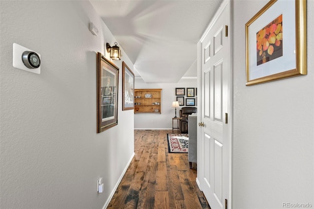 corridor featuring dark wood-style flooring and baseboards