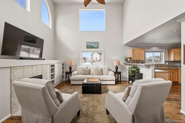 living area featuring ceiling fan, recessed lighting, a fireplace, wood finished floors, and baseboards