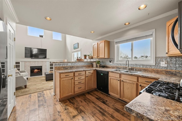 kitchen with a sink, dark wood-style floors, open floor plan, dishwasher, and a tiled fireplace