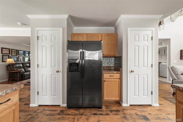 kitchen featuring open floor plan, decorative backsplash, stainless steel fridge, dark wood finished floors, and washer / dryer