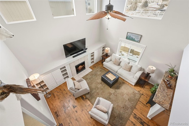 living area featuring a fireplace, visible vents, light wood-style flooring, ceiling fan, and baseboards